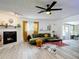 Living room features a white brick fireplace, green sofa, and large windows with modern ceiling fan at 1421 Pine Tree Dr, Edgewater, FL 32132