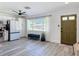 Bright living room featuring modern wood flooring, a white refrigerator and an olive-colored entry door at 1421 Pine Tree Dr, Edgewater, FL 32132