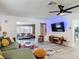 Open-concept living room with green sectional sofa, media center, and a view into sunroom at 1421 Pine Tree Dr, Edgewater, FL 32132
