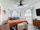 Comfortable main bedroom featuring a ceiling fan, hardwood floors, and plentiful light from a large window at 1421 Pine Tree Dr, Edgewater, FL 32132