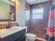 Bathroom with brick shower, white sink, black vanity, and patterned shower curtain at 156 S State Road 415, New Smyrna Beach, FL 32168