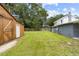 A spacious backyard with a wooden barn and a gray and white house at 2005 Sunny Ln, New Smyrna Beach, FL 32168