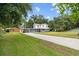 Exterior view of a gray and white two-story home with a long driveway and lush green lawn at 2005 Sunny Ln, New Smyrna Beach, FL 32168