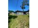 Exterior shot of house backyard with plenty of green grass, wooden fence, and a shady tree at 2122 Orange Tree Dr, Edgewater, FL 32141
