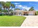 Charming single-story stone home featuring a lush front lawn and brick-paved driveway at 22 Sand Dune Dr, New Smyrna Beach, FL 32169