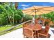 Outdoor patio area with a dark wood table with an umbrella, chairs, and a grill at 22 Sand Dune Dr, New Smyrna Beach, FL 32169
