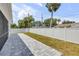 Backyard featuring a paved patio, grassy area, and a white fence with trees in the background at 2324 Orange Tree Dr, Edgewater, FL 32141