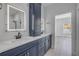 Contemporary bathroom featuring double vanity with blue cabinets, lighted mirrors, a shower, and a doorway to another room at 2324 Orange Tree Dr, Edgewater, FL 32141