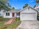 Exterior front of home with red door, lush landscaping and attached two-car garage and concrete driveway at 255 Lexington Dr, Daytona Beach, FL 32114