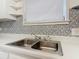 Bright kitchen featuring a stainless steel dual sink and unique, patterned backsplash at 255 Lexington Dr, Daytona Beach, FL 32114