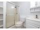 This bathroom features a shower with glass doors, toilet and vanity with sink and wall storage at 2617 Pine Tree Dr, Edgewater, FL 32141