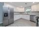 Bright kitchen features stainless appliances, white cabinets, modern backsplash, and tile flooring at 2617 Pine Tree Dr, Edgewater, FL 32141