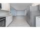 Bright kitchen with stainless appliances, white cabinets and adjacent living area with matching tile floor at 2617 Pine Tree Dr, Edgewater, FL 32141