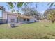 Spacious backyard with green grass, a chicken coop, and a fire pit area perfect for outdoor entertaining at 2715 Pine Tree Dr, Edgewater, FL 32141