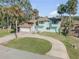 Two-story home with circular driveway, attached garage, mature palms accentuating the facade, creating a tropical vibe at 2715 Pine Tree Dr, Edgewater, FL 32141