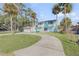 Beautiful two-story home with a circular driveway, attached garage, surrounded by lush greenery and mature palm trees at 2715 Pine Tree Dr, Edgewater, FL 32141