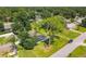 Aerial view showing mature trees surrounding a carport-style home featuring lush lawn and mature landscaping at 3045 Pine Tree Dr, Edgewater, FL 32141