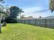 A well-kept backyard with a healthy lawn and a tall wooden fence line, surrounded by shady trees at 3045 Pine Tree Dr, Edgewater, FL 32141