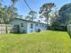 A lush backyard with a well-maintained lawn, wood fence, and the exterior of a light-blue house at 3045 Pine Tree Dr, Edgewater, FL 32141