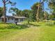 Single-story home surrounded by green lawn and mature trees at 3045 Pine Tree Dr, Edgewater, FL 32141