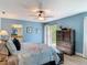 Bedroom with light blue walls, hardwood floors, dresser, access to bathroom, and view of the yard at 343 Sweet Bay Ave, New Smyrna Beach, FL 32168