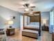Bedroom with a wooden canopy bed, wood floors, and bench seat, creating a cozy atmosphere at 343 Sweet Bay Ave, New Smyrna Beach, FL 32168