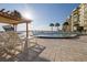 Condo community pool area with shaded pergola, sun chairs, and waterfront views under a sunny sky at 3606 S Peninsula Dr # 406, Port Orange, FL 32127