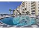 Community pool area with condo building, tropical landscaping, and waterfront views at 3606 S Peninsula Dr # 406, Port Orange, FL 32127