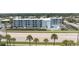 Expansive aerial view of the condo building featuring a pool, parking, beach access and surrounding residential neighborhood at 3700 S Atlantic Ave # 108, New Smyrna Beach, FL 32169
