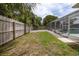 A partial shot of the backyard, enclosed pool, and backyard wooden fence, partially covered with local foliage at 38 Fairway Cir, New Smyrna Beach, FL 32168