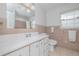 Cozy bathroom with white vanity, pink tiling, and a window for natural light at 38 Fairway Cir, New Smyrna Beach, FL 32168