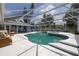 A wide angle shot of the enclosed kidney shaped pool, a jacuzzi and a view of the home's backyard at 38 Fairway Cir, New Smyrna Beach, FL 32168