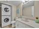 Cozy bathroom with stacked washer and dryer, white vanity, and tiled floor at 3824 Saxon Dr, New Smyrna Beach, FL 32169