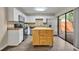 White kitchen with an island, stainless steel appliances, tile backsplash, and sliding glass doors at 3824 Saxon Dr, New Smyrna Beach, FL 32169