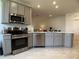 Modern kitchen featuring gray cabinets, stainless steel appliances, and a view into the adjacent living spaces at 3919 Willowbrook Dr, Edgewater, FL 32141