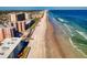 Long, sandy beach with waves crashing and condominium buildings in the background at 4141 S Atlantic Ave # 605, New Smyrna Beach, FL 32169