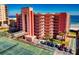 Expansive view of the building's exterior featuring balconies, tropical trees, and a tennis court in view at 4141 S Atlantic Ave # 605, New Smyrna Beach, FL 32169