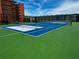 View of tennis court with a lush green surface and lines, next to apartment buildings at 4141 S Atlantic Ave # 605, New Smyrna Beach, FL 32169