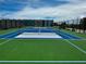 Close-up view of a bright green and blue outdoor tennis court at 4141 S Atlantic Ave # 605, New Smyrna Beach, FL 32169