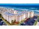 Aerial view of beachfront condos with a pool, lush landscaping, and ample parking at 4175 S Atlantic Ave # 4110, New Smyrna Beach, FL 32169