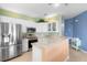 Modern kitchen with white cabinets, stainless appliances, and eat-in counter, open to adjacent living space at 438 Bouchelle Dr # 105, New Smyrna Beach, FL 32169