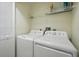This laundry room features a white washer and dryer set along with a wire shelf for storage at 454 Bouchelle Dr # 102, New Smyrna Beach, FL 32169