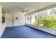 Enclosed porch featuring blue carpet, ceiling fan, and large windows offering plenty of natural light at 5060 Audubon Ave, De Leon Springs, FL 32130
