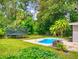 Secluded backyard featuring lush landscaping, a trampoline and a small swimming pool at 5476 W Bayshore Dr, Port Orange, FL 32127