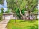 Charming single-story home with mature trees, a well-maintained lawn, and an attached garage at 5476 W Bayshore Dr, Port Orange, FL 32127