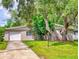 Well-maintained home featuring a garage, a driveway, and lush mature landscaping at 5476 W Bayshore Dr, Port Orange, FL 32127