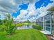 View of the backyard featuring a screened pool, well-maintained lawn, and a serene pond at 6804 Forkmead Ln, Port Orange, FL 32128