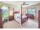 Comfortable main bedroom featuring a four-poster bed, ceiling fan and backyard views at 6804 Forkmead Ln, Port Orange, FL 32128