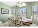 Bright dining area with wooden table, white chairs, and multiple windows overlooking the outdoors at 684 Rochester Ct, New Smyrna Beach, FL 32168