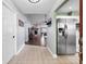 Open-concept hallway with a glimpse into the living room and adjacent stainless steel refrigerator in kitchen at 684 Rochester Ct, New Smyrna Beach, FL 32168